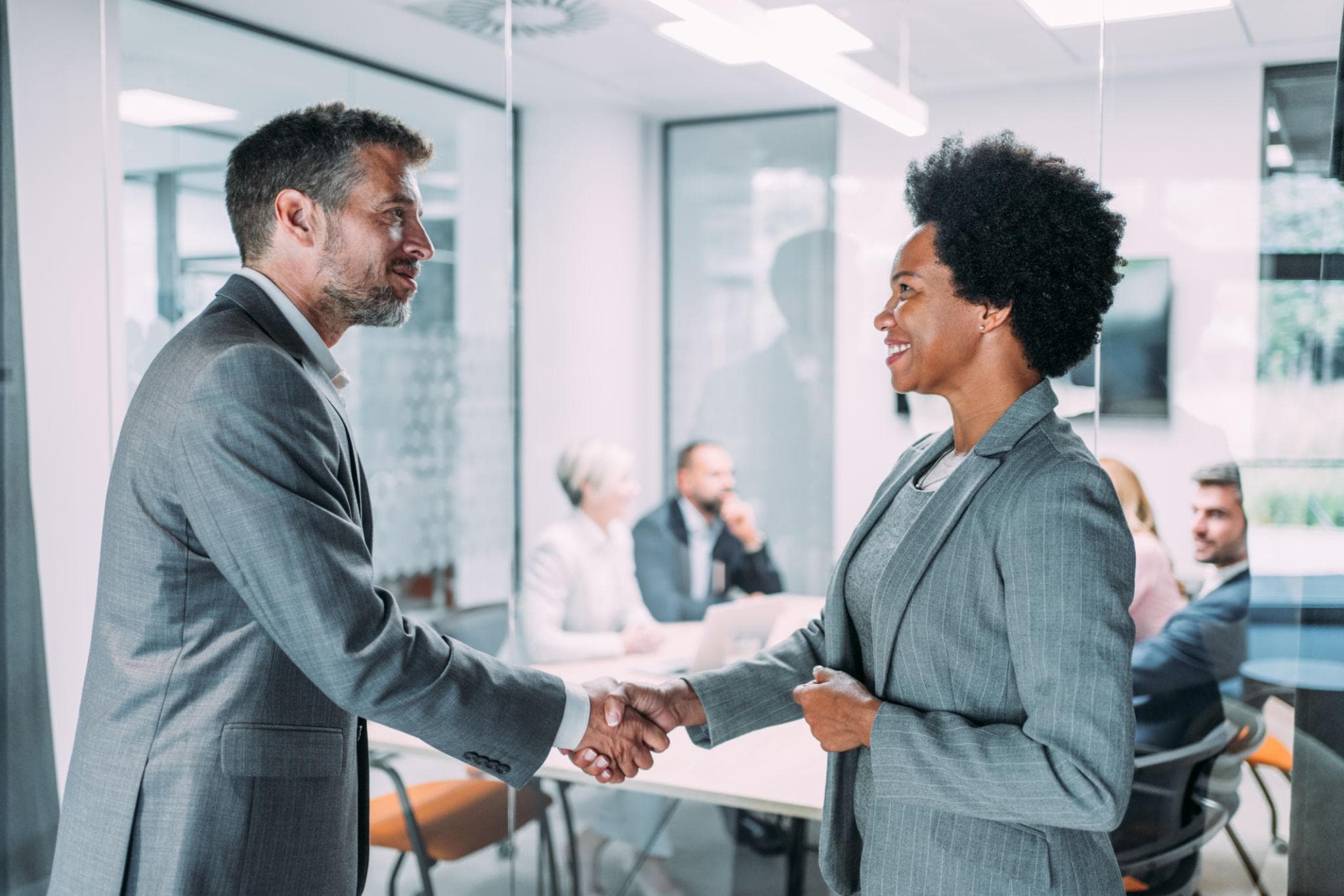 A recruitment consultant greeting a client partner with a handshake.